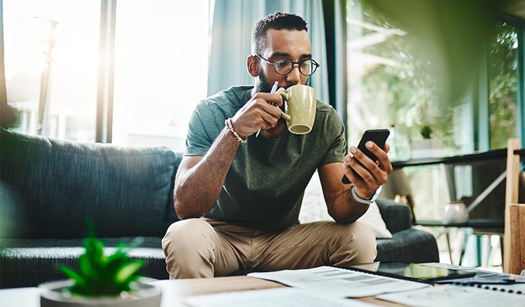 African American Man On Couch Using Smartphone